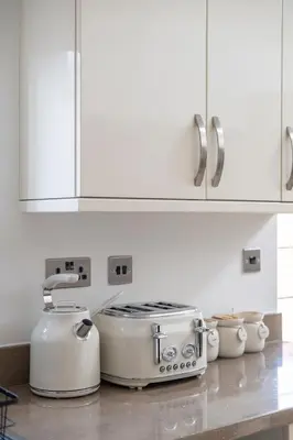 a kitchen with white cabinets and two toasters on a counter at The Romford Oasis - Spacious 4 bedroom escape in Havering atte Bower