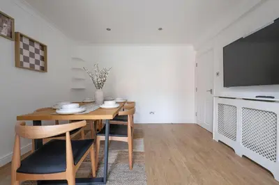 a dining room with a table and a television at The Romford Oasis - Spacious 4 bedroom escape in Havering atte Bower