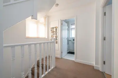 a hallway with white walls and a stairway at The Romford Oasis - Spacious 4 bedroom escape in Havering atte Bower