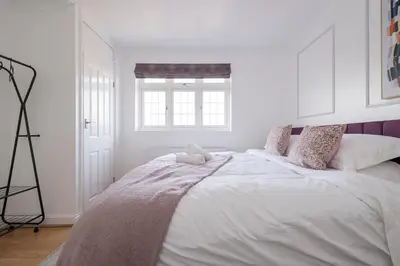 a white bedroom with a large bed with a teddy bear on it at The Romford Oasis - Spacious 4 bedroom escape in Havering atte Bower