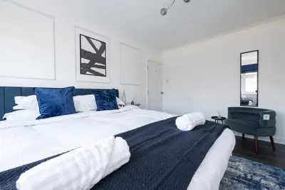 a bedroom with a large white bed with blue pillows at The Romford Oasis - Spacious 4 bedroom escape in Havering atte Bower