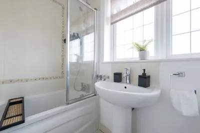 a white bathroom with a sink and a shower at The Romford Oasis - Spacious 4 bedroom escape in Havering atte Bower