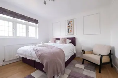 a bedroom with a large bed and a chair at The Romford Oasis - Spacious 4 bedroom escape in Havering atte Bower