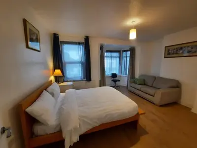 a bedroom with a large bed and a couch at Seafront 2-Bed Apt Sleeps 4 in Clacton-on-Sea in Clacton-on-Sea