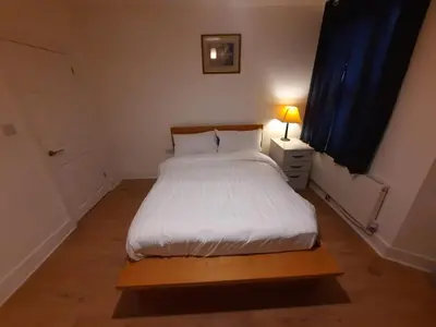 a bedroom with a white bed with a night stand and a lamp at Seafront 2-Bed Apt Sleeps 4 in Clacton-on-Sea in Clacton-on-Sea