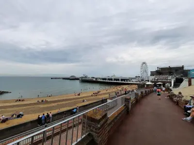 a beach with a pier and people on the beach at Seafront 2-Bed Apt Sleeps 4 in Clacton-on-Sea in Clacton-on-Sea