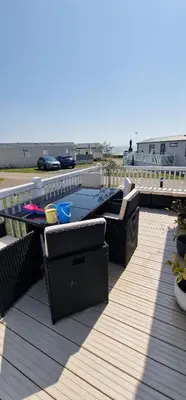a patio with a table and chairs on a deck at The Beach House East Mersea in Mersea Island