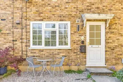 a table and two chairs in front of a brick building at Cozy Riverside Cottage in Hertford Town with Parking in Hertford
