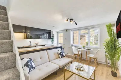 a living room with a white couch and a table at Cozy Riverside Cottage in Hertford Town with Parking in Hertford