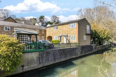 a house next to a river with buildings at Cozy Riverside Cottage in Hertford Town with Parking in Hertford