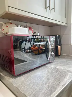 a red microwave on a kitchen counter with food at Golden House in Waterbeach