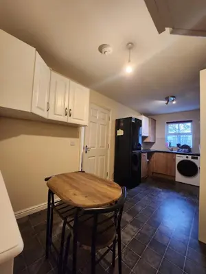 a kitchen with a wooden table and a black refrigerator at Cosy En-suite Rooms - Ipswich in Ipswich
