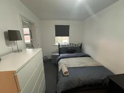 a bedroom with a bed and a dresser in it at Cosy En-suite Rooms - Ipswich in Ipswich