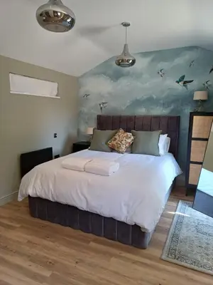 a bedroom with a large bed with a painting on the wall at The Beehive Inn in Bury Saint Edmunds