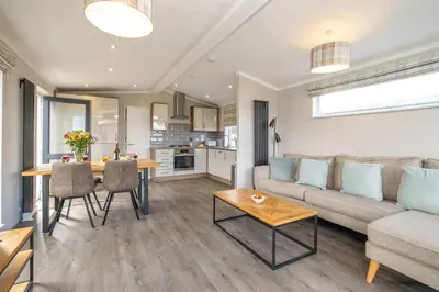 a living room with a couch and a table at Driftwood Lodge, Sizewell - Adults only property - Aldeburgh Coastal Cottages in Sizewell