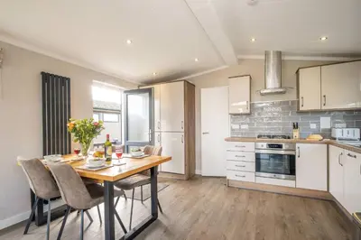 a kitchen with a wooden table and chairs in a room at Driftwood Lodge, Sizewell - Adults only property - Aldeburgh Coastal Cottages in Sizewell