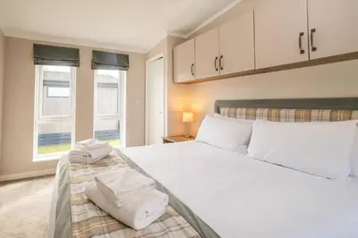 a bedroom with a large white bed with towels on it at Driftwood Lodge, Sizewell - Adults only property - Aldeburgh Coastal Cottages in Sizewell