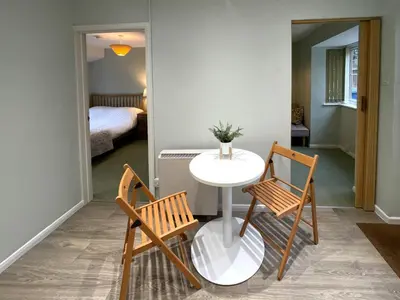 a table and two chairs in a room with a bedroom at Cosy Home Opposite Addenbrookes Hospital - Free Parking in Cambridge