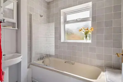a bathroom with a tub and a vase of flowers in a window at 3 Bed in Bawdsey oc-p31139 in Bawdsey