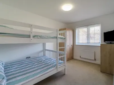 a bedroom with two bunk beds and a flat screen tv at 21 Skippers Way in Walton-on-the-Naze