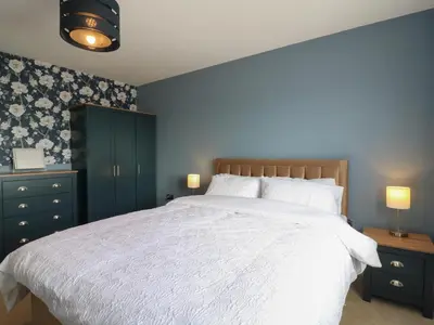 a bedroom with a white bed and blue walls at 21 Skippers Way in Walton-on-the-Naze