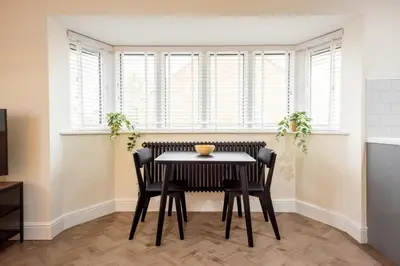 a dining room with a table and chairs and windows at 8 The Royal Serviced Apartments ,Harwich, One Bed Parking, Fast Wifi, Space Apartments in Parkeston