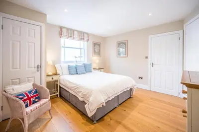 a bedroom with a bed and a chair at Market Cross House, Aldeburgh. Sea front holiday home in Aldeburgh