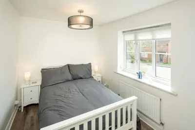 a white bedroom with a bed and a window at Loughton Hideaway: Cozy 1BD Near Tube & Nature in Theydon Bois