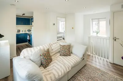 a white couch in a living room with blue cabinets at Loughton Hideaway: Cozy 1BD Near Tube & Nature in Theydon Bois