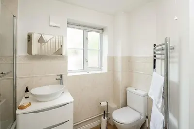 a white bathroom with a toilet and a sink at Loughton Hideaway: Cozy 1BD Near Tube & Nature in Theydon Bois