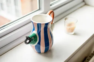 a striped vase sitting on a window sill at Loughton Hideaway: Cozy 1BD Near Tube & Nature in Theydon Bois