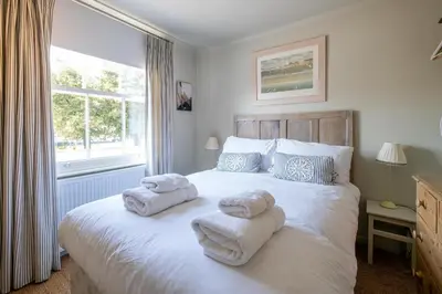 a bedroom with towels on a bed with a window at Seagulls - Aldeburgh Coastal Cottages in Aldeburgh