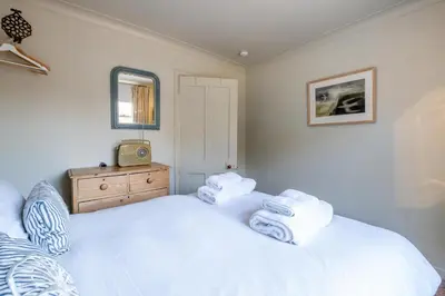a bedroom with a white bed and a mirror at Seagulls - Aldeburgh Coastal Cottages in Aldeburgh