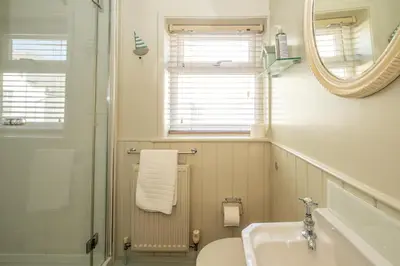 a bathroom with a sink and a toilet and a mirror at Seagulls - Aldeburgh Coastal Cottages in Aldeburgh