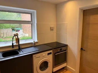 a kitchen with a washing machine and a window at Apartment close to London Stansted airport in Great Parndon