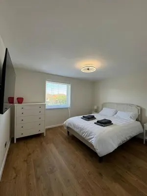 a bedroom with a bed and a dresser and a television at Fantastic family flat in Frinton in Kirby Cross