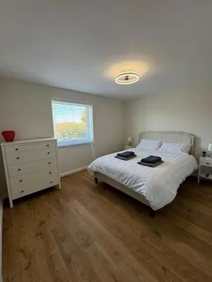 a bedroom with a bed and a dresser and a window at Fantastic family flat in Frinton in Kirby Cross