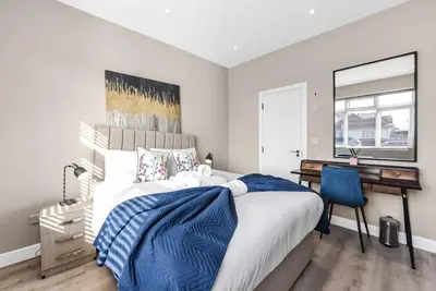 a bedroom with a bed with a desk and a blue chair at Studio Society - Stay, Cook, and Connect in Southend-on-Sea