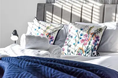a bed with white sheets and pillows on it at Studio Society - Stay, Cook, and Connect in Southend-on-Sea
