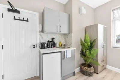 a kitchen with white cabinets and a sink at Studio Society - Stay, Cook, and Connect in Southend-on-Sea