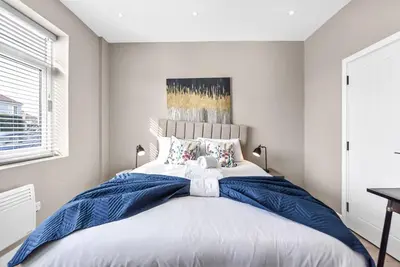 a bedroom with a large bed with a blue blanket at Studio Society - Stay, Cook, and Connect in Southend-on-Sea