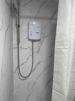 a shower in a bathroom with white marble walls at Cozy mini studio in Basildon in Nevendon