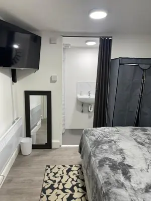 a bedroom with a bed and a sink and a mirror at Cozy mini studio in Basildon in Nevendon