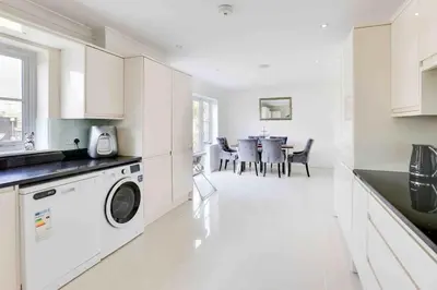 a white kitchen with a washer and dryer in it at Wayside Warren Harlow in Potter Street