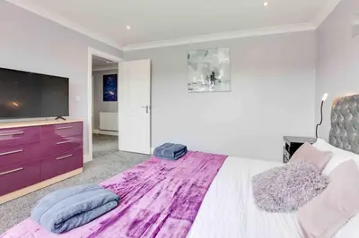 a bedroom with a large bed and a flat screen tv at Wayside Warren Harlow in Potter Street