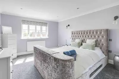 a bedroom with a large bed with a large headboard at Wayside Warren Harlow in Potter Street