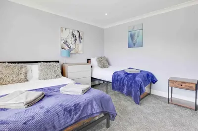 a bedroom with two beds and a table in it at Wayside Warren Harlow in Potter Street