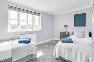 a white bedroom with two beds and a window at Wayside Warren Harlow in Potter Street