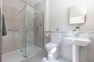 a bathroom with a shower and a toilet and a sink at Stylish Coach House Retreat in Wymondham