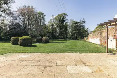 a yard with a stone walkway with bushes and trees at Stylish Coach House Retreat in Wymondham